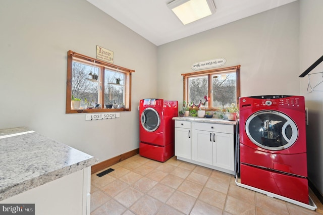 clothes washing area with visible vents, independent washer and dryer, cabinet space, light tile patterned flooring, and baseboards