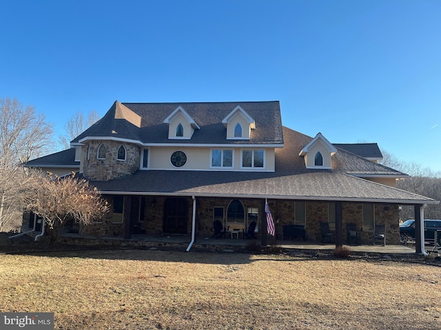 view of front of home with stone siding, a patio, and a front lawn