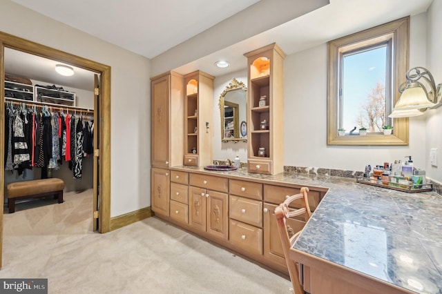 bathroom with vanity, a walk in closet, and baseboards