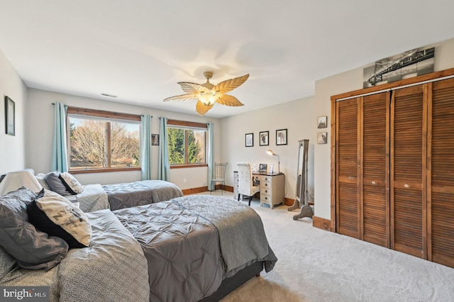 carpeted bedroom with visible vents, baseboards, a closet, and ceiling fan