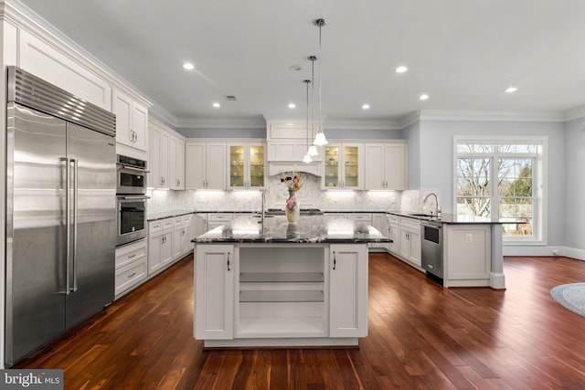 kitchen with decorative backsplash, glass insert cabinets, a peninsula, stainless steel appliances, and crown molding