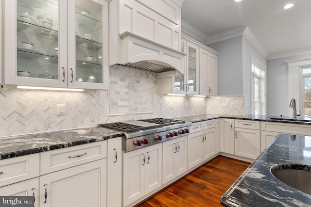 kitchen with white cabinets, dark stone counters, ornamental molding, stainless steel gas stovetop, and a sink