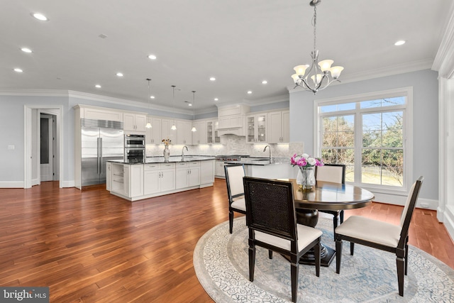 dining space with dark wood-style floors, ornamental molding, and a notable chandelier