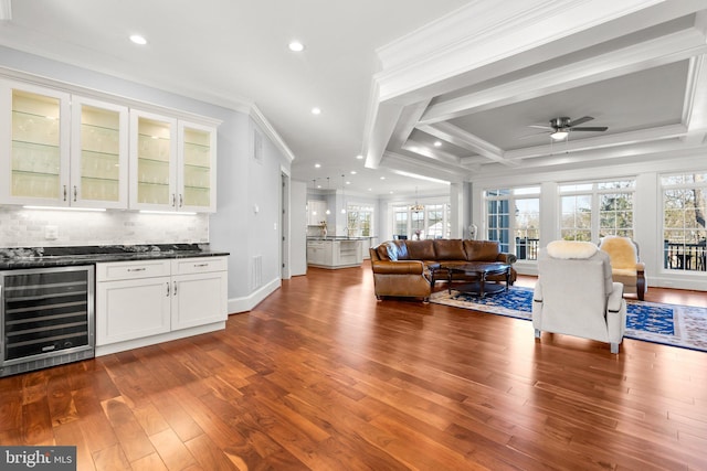 living room with ornamental molding, beverage cooler, a healthy amount of sunlight, and a bar