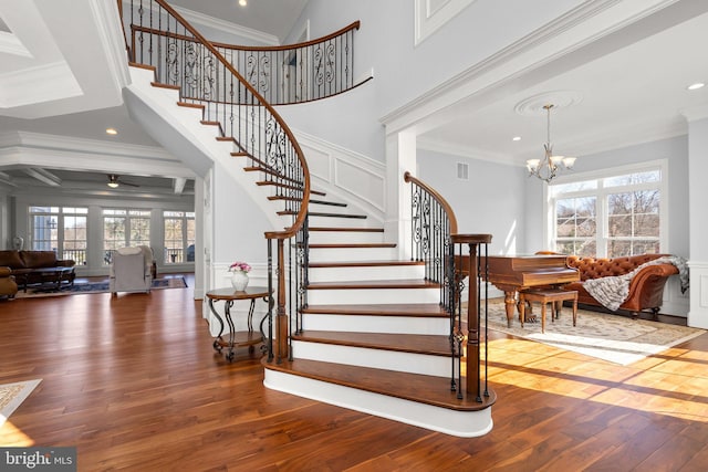 staircase featuring crown molding, hardwood / wood-style floors, a chandelier, and a healthy amount of sunlight