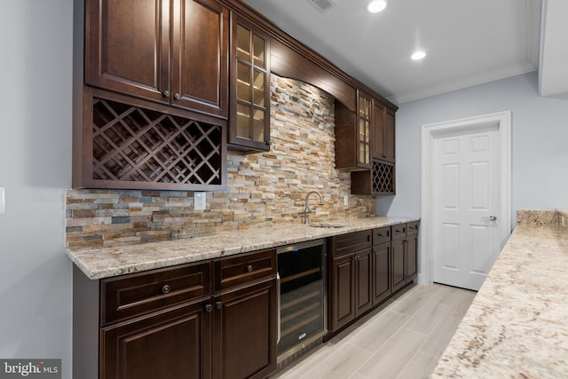 bar with tasteful backsplash, wine cooler, ornamental molding, a sink, and indoor wet bar