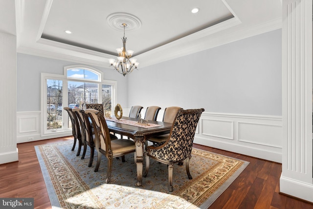 dining room with a chandelier, a tray ceiling, dark wood-type flooring, and crown molding