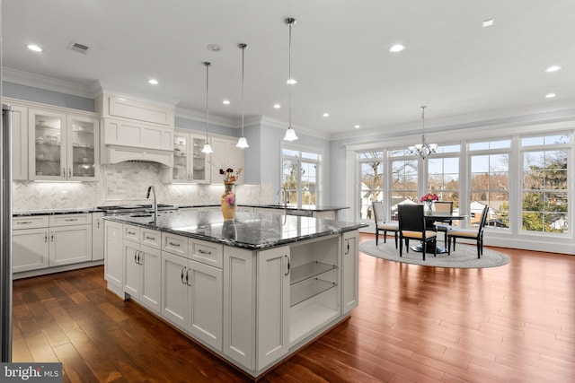 kitchen with visible vents, a sink, backsplash, and an island with sink