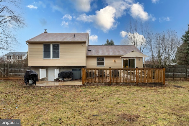 rear view of property with a fenced backyard, a lawn, a wooden deck, and a patio