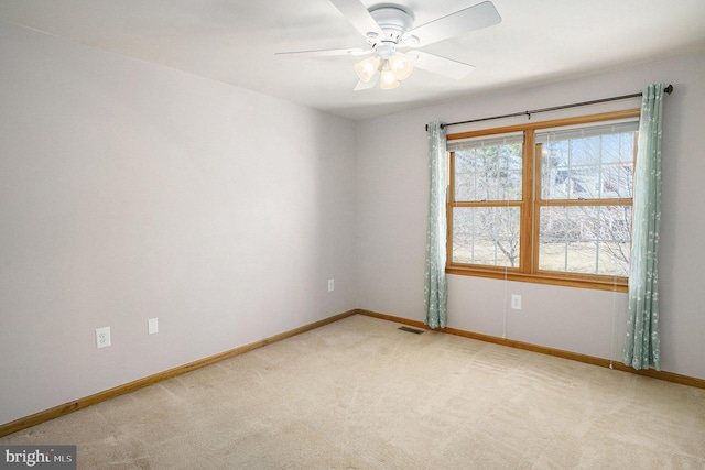 spare room with visible vents, light carpet, baseboards, and a ceiling fan