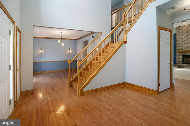 stairway with hardwood / wood-style floors, an inviting chandelier, baseboards, and a towering ceiling