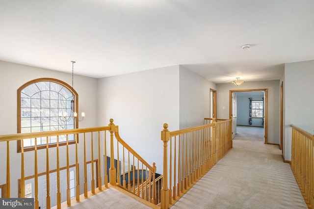 hall with an upstairs landing, a chandelier, and carpet floors