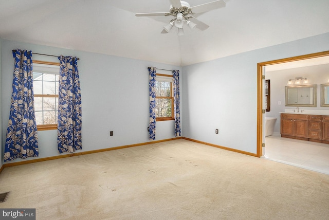 unfurnished bedroom featuring visible vents, baseboards, lofted ceiling, carpet flooring, and ensuite bath