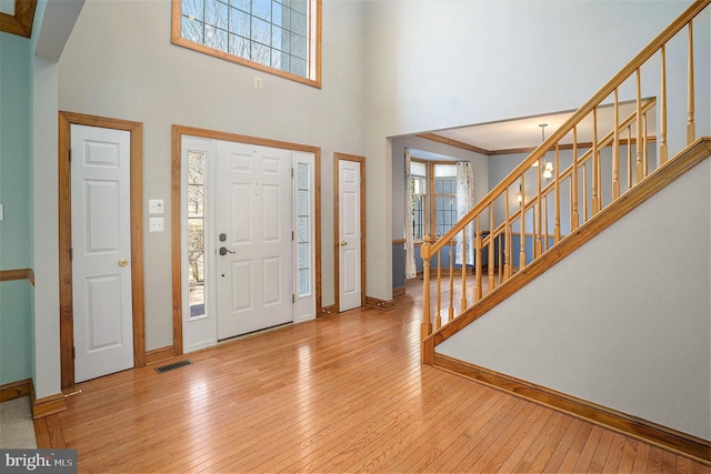 foyer featuring visible vents, hardwood / wood-style flooring, baseboards, a towering ceiling, and stairs