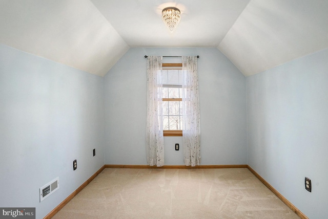 additional living space featuring light carpet, visible vents, and baseboards