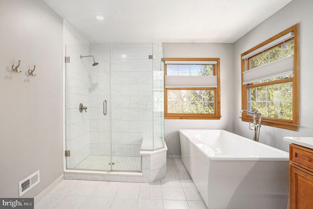 bathroom with visible vents, a shower stall, baseboards, a soaking tub, and vanity