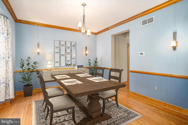 dining room featuring light wood-type flooring, visible vents, baseboards, and crown molding