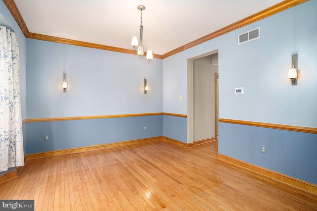 spare room featuring visible vents, ornamental molding, baseboards, and hardwood / wood-style floors