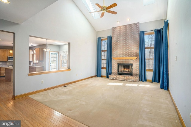 unfurnished living room with high vaulted ceiling, plenty of natural light, baseboards, and ceiling fan