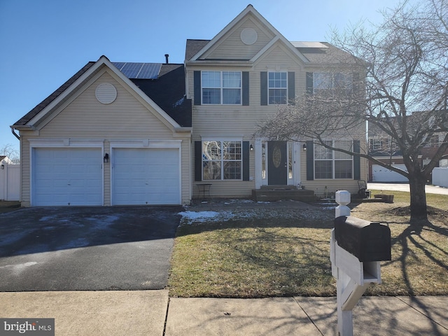 view of front of property featuring driveway, an attached garage, and solar panels