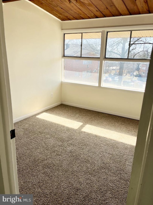 carpeted empty room featuring wood ceiling and baseboards