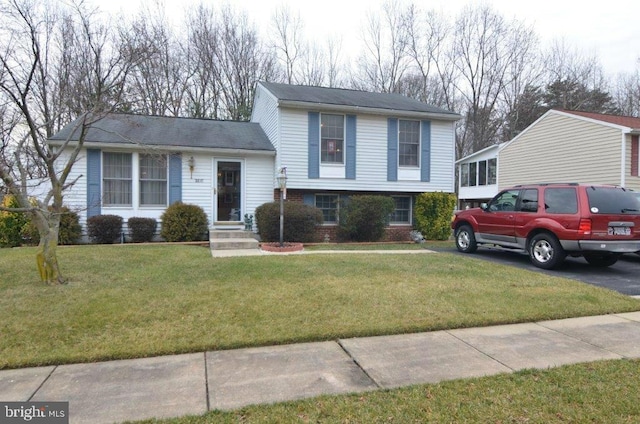 tri-level home featuring brick siding and a front yard