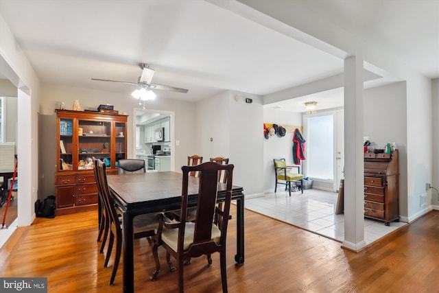 dining room with light wood-style floors, ceiling fan, and baseboards