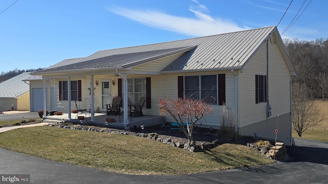 view of front of house with metal roof, a porch, and a front yard