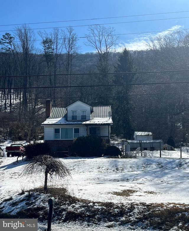 view of front of property with a chimney and metal roof