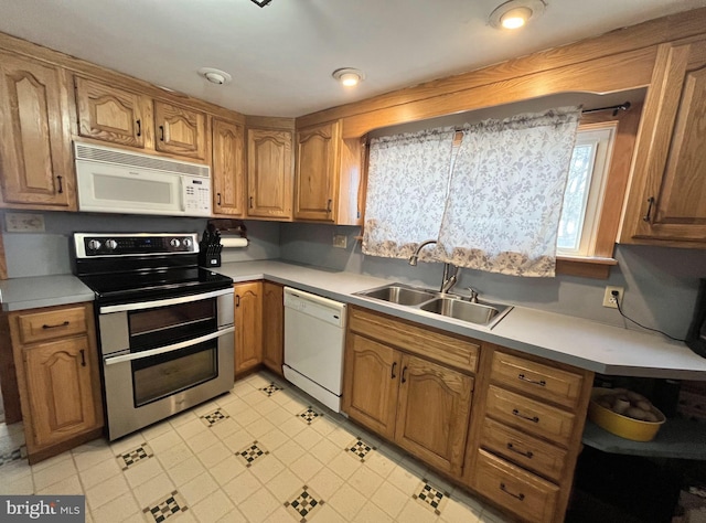 kitchen featuring brown cabinets, white appliances, light countertops, and a sink