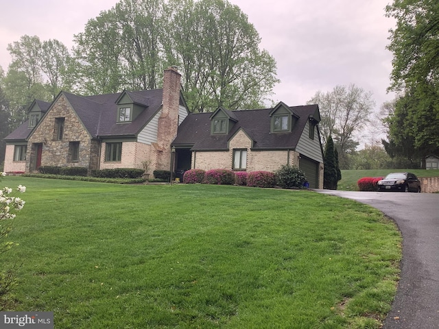 view of front of property featuring a garage, a front lawn, aphalt driveway, and brick siding