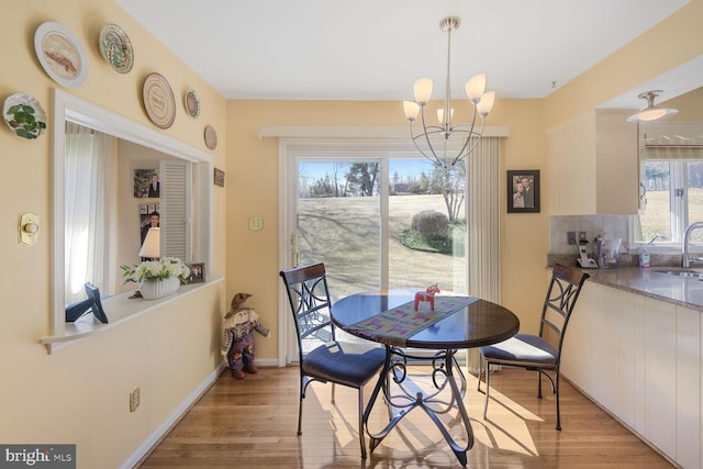 dining area with baseboards, light wood-type flooring, and a notable chandelier