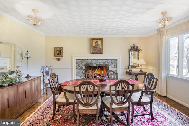 dining space with ornamental molding, a fireplace, and baseboards