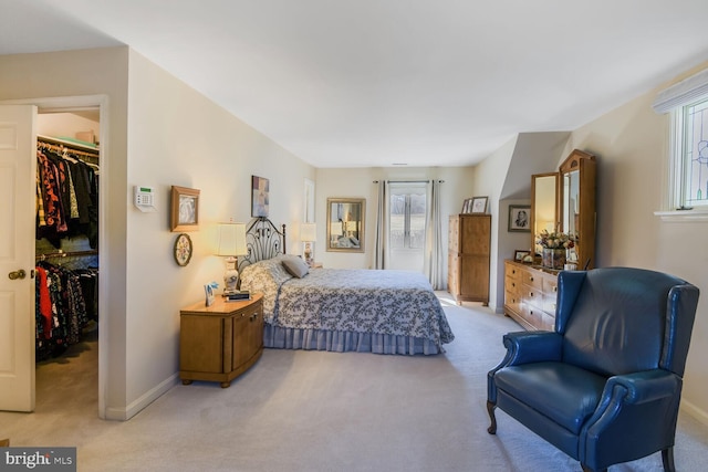 bedroom featuring a closet, light carpet, a spacious closet, and baseboards