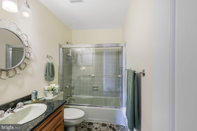 full bathroom featuring visible vents, shower / bath combination with glass door, vanity, and toilet