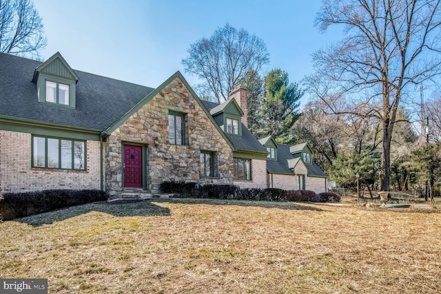 view of front facade featuring a chimney, a front lawn, and brick siding