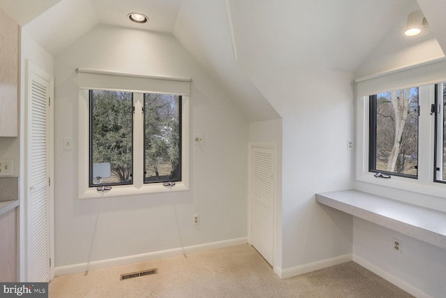 bonus room featuring light colored carpet, lofted ceiling, visible vents, and baseboards