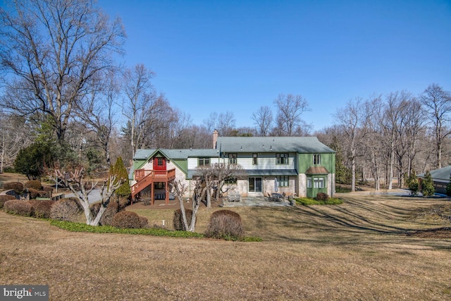 view of front of home featuring a deck, a front yard, stairs, a chimney, and a patio area