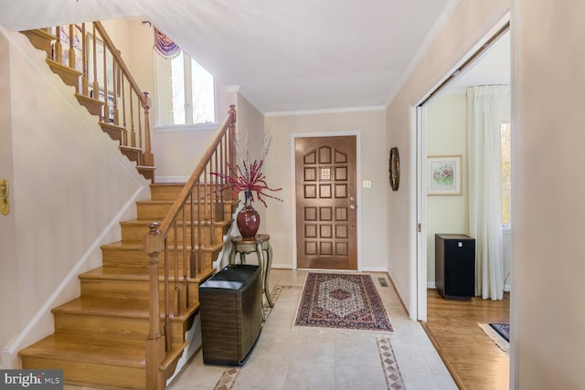 foyer entrance with baseboards, ornamental molding, and tile patterned floors