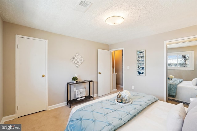 bedroom featuring carpet floors, baseboards, visible vents, and a textured ceiling