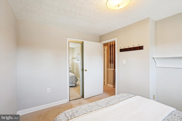 bedroom with a closet, a textured ceiling, and light colored carpet