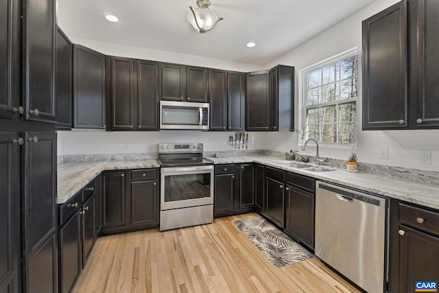 kitchen with appliances with stainless steel finishes, recessed lighting, a sink, and light wood finished floors