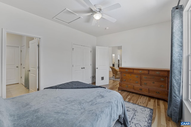 bedroom with light wood-style floors, attic access, and ceiling fan