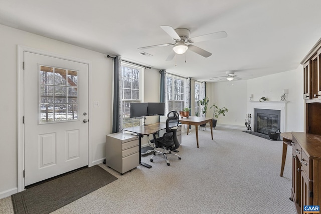 office featuring light carpet, a fireplace with flush hearth, visible vents, and baseboards