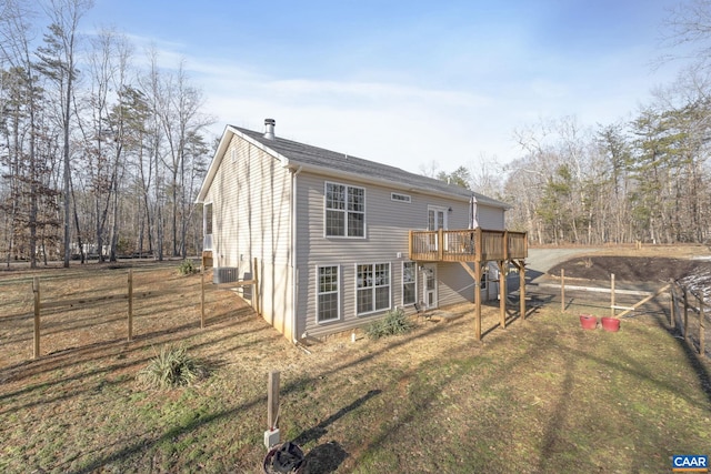 back of property with fence, a deck, and a lawn