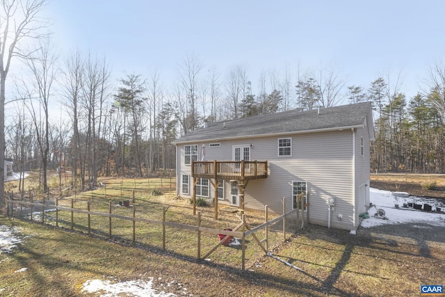 rear view of property with fence, a wooden deck, and a lawn