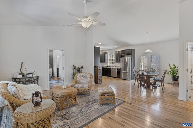 living room with light wood-type flooring, baseboards, high vaulted ceiling, and a ceiling fan