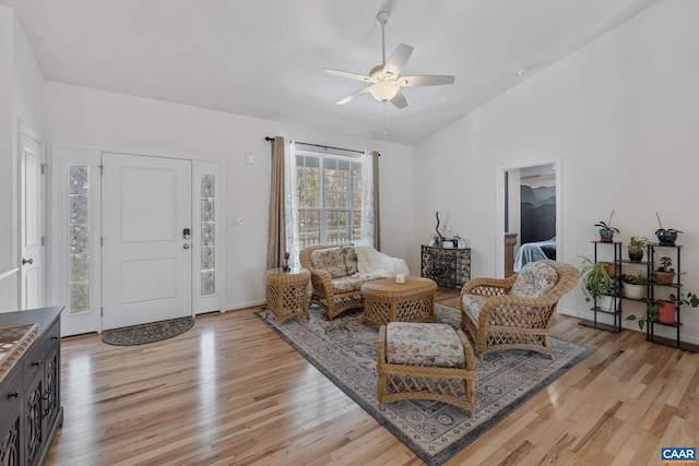 living area featuring a ceiling fan, lofted ceiling, light wood-style flooring, and baseboards