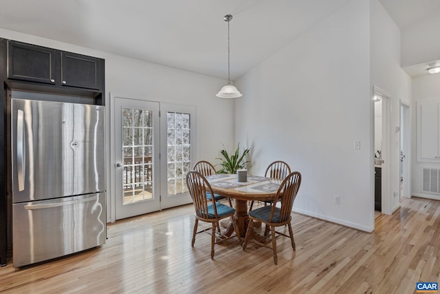 dining room with light wood-style floors, visible vents, high vaulted ceiling, and baseboards