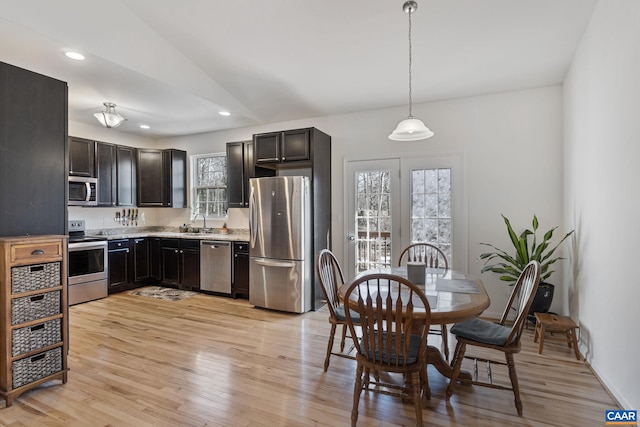 kitchen with light wood-style flooring, appliances with stainless steel finishes, light countertops, pendant lighting, and a sink